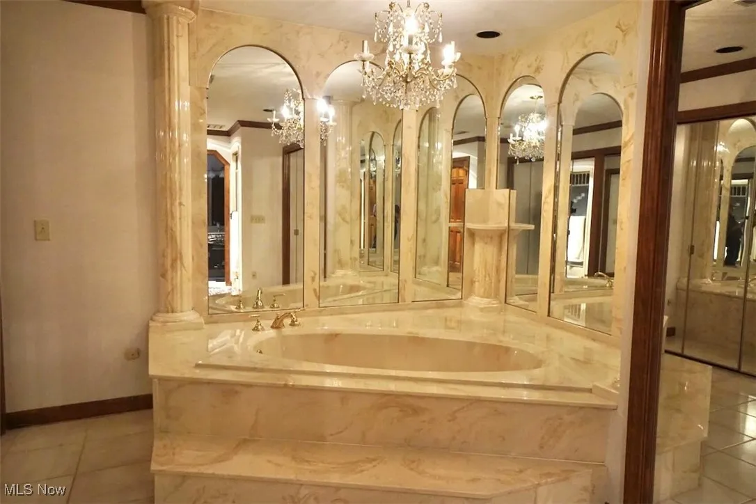 Master bath soaking tub  tile patterned floors, and a chandelier
