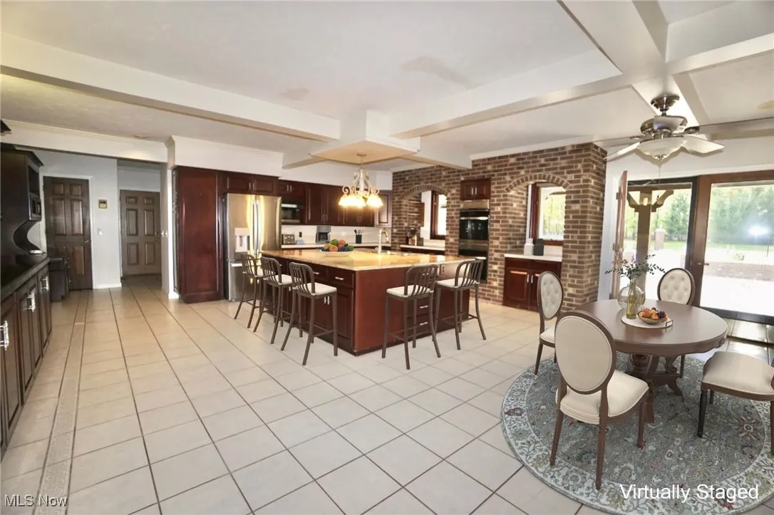 Kitchen space featuring beamed ceiling, light tile patterned flooring, huge island and space to eat-in.