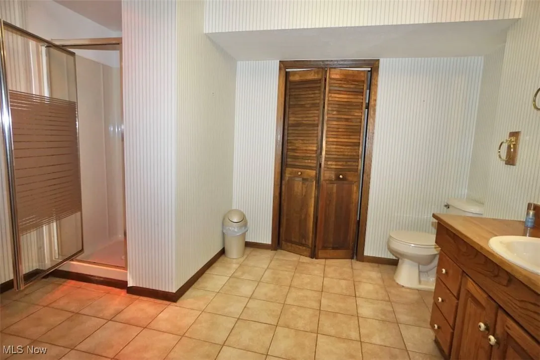 Lower level bathroom with vanity, a stall shower, and light tile patterned floors