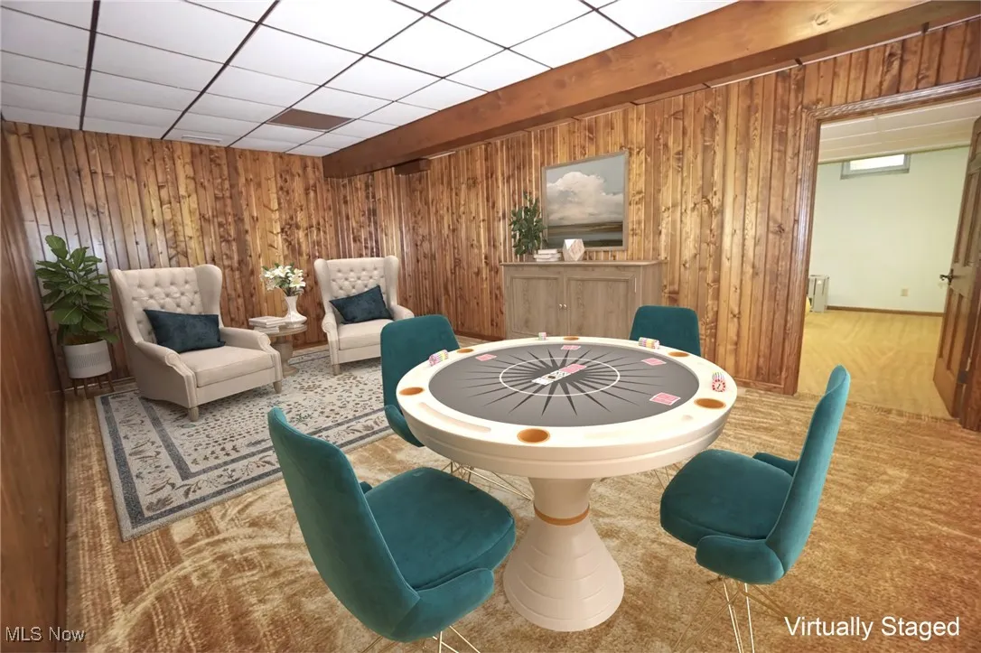 Dining space featuring wood walls, a drop ceiling, carpet, and beam ceiling