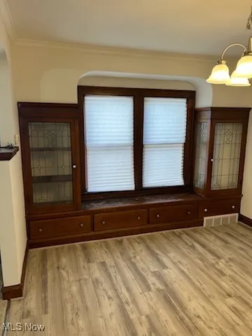 Unfurnished room with crown molding and light wood-style flooring