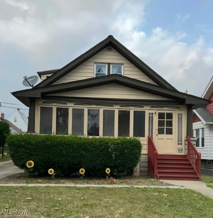 Bungalow with entry steps, a front lawn, and a sunroom