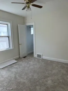 Empty room with healthy amount of natural light, carpet, and a ceiling fan