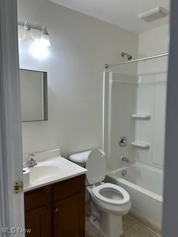 Full bath with shower / bathtub combination, vanity, a textured ceiling, and light tile patterned floors