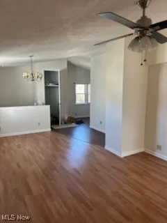 Spare room with dark wood-type flooring, a chandelier, and ceiling fan