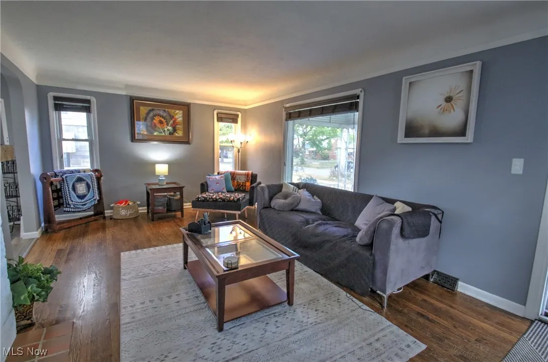 Living room featuring dark wood-style flooring and ornamental molding