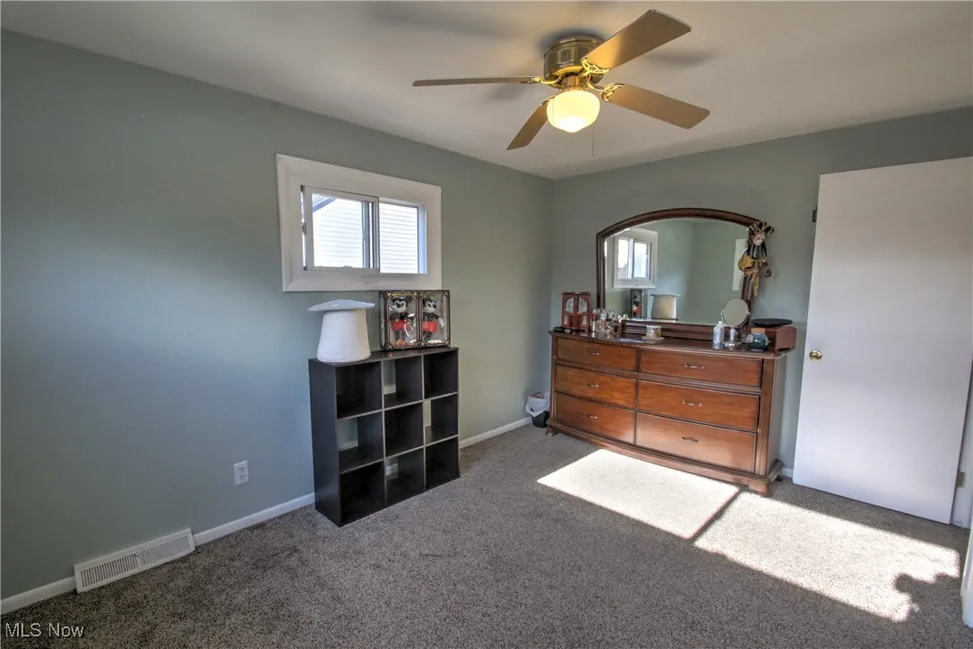 Bedroom featuring multiple windows, light carpet, and ceiling fan