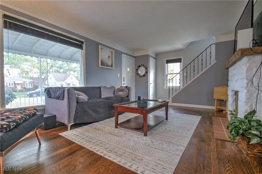 Living area featuring a decorative fireplace, dark wood-style floors, and stairway