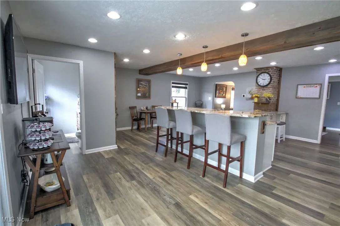 Kitchen featuring beamed ceiling, light granite counters, recessed lighting, a kitchen breakfast bar, and decorative light fixtures