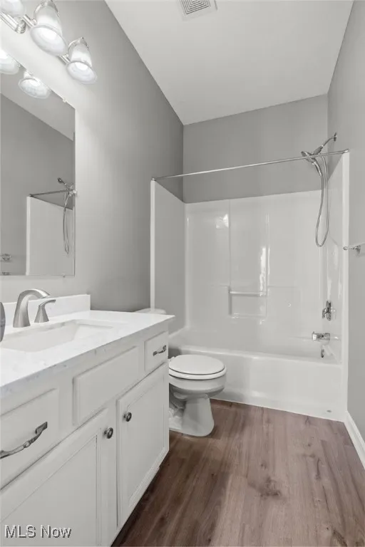 Full bathroom featuring  shower combination, vanity, and dark wood-style flooring