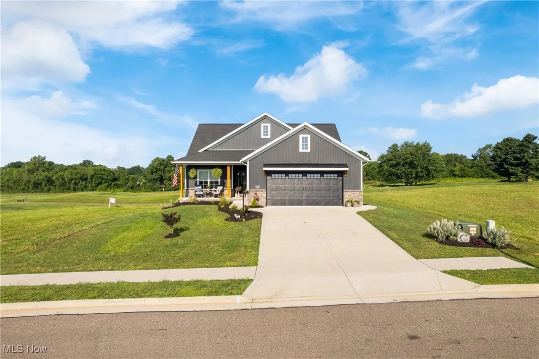 Craftsman house featuring stone siding, a porch, a front yard, and concrete driveway
