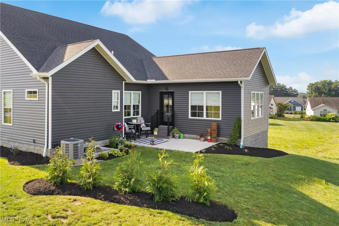 Back of house with a patio area, roof with shingles, and a yard