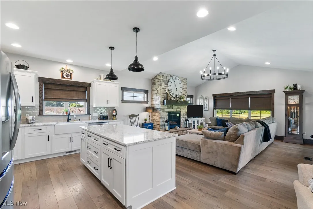 Kitchen featuring white cabinets, a kitchen island, stainless steel fridge, light wood-style floors, and lofted ceiling