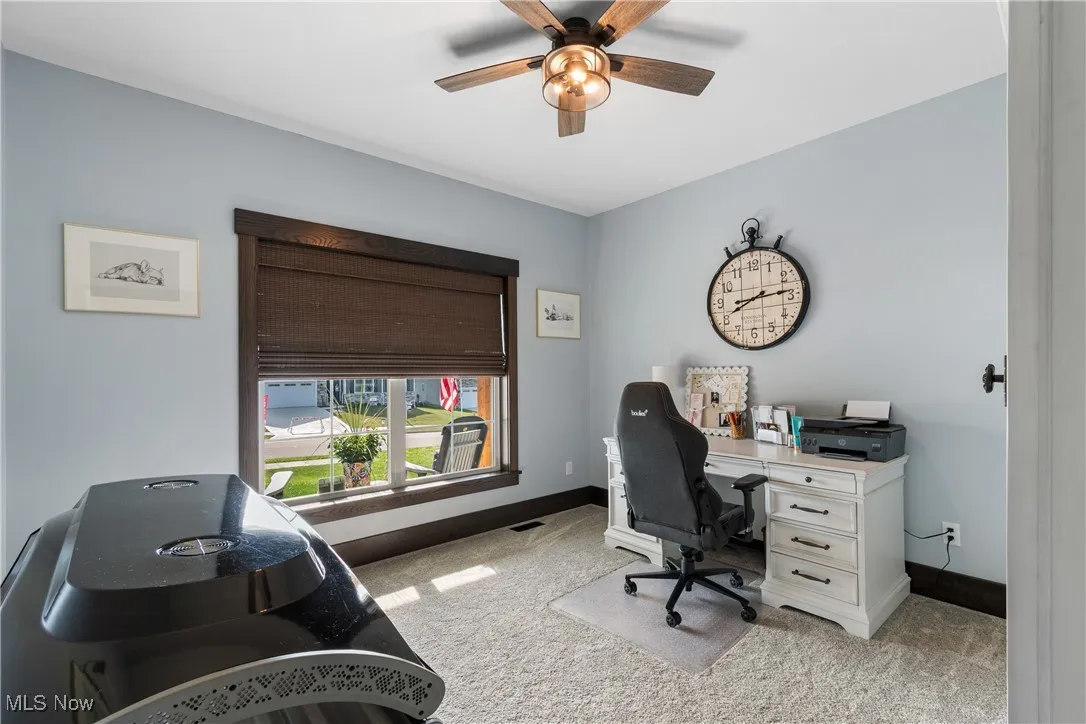 Home office with light colored carpet and a ceiling fan