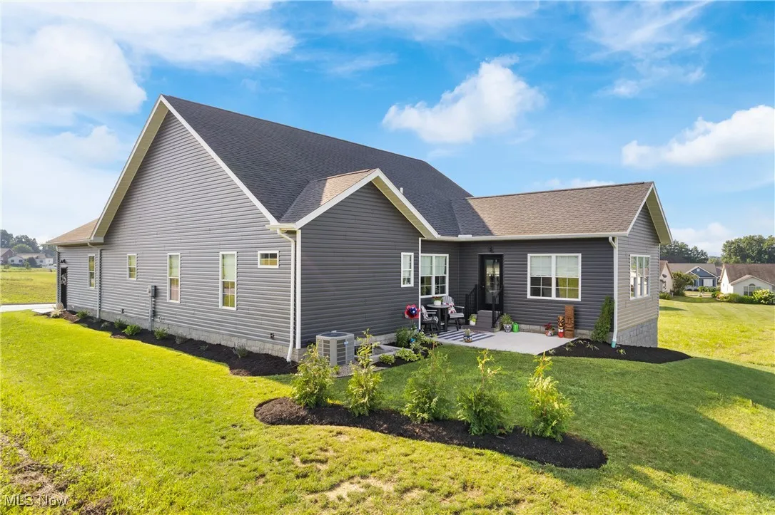Back of property featuring a lawn, a shingled roof, and a patio area