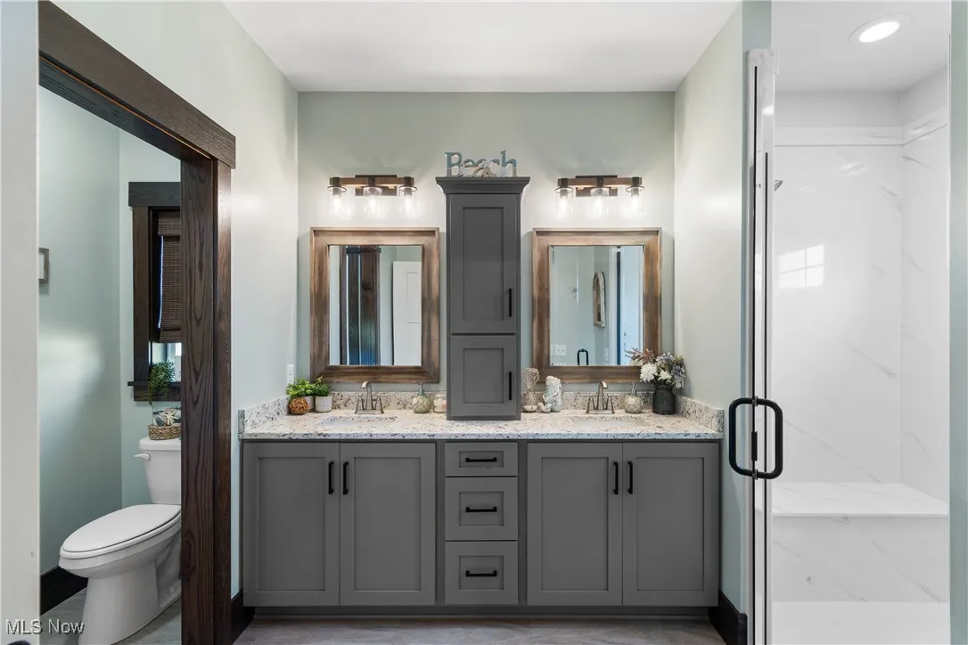 Full bath featuring double vanity and a marble finish shower