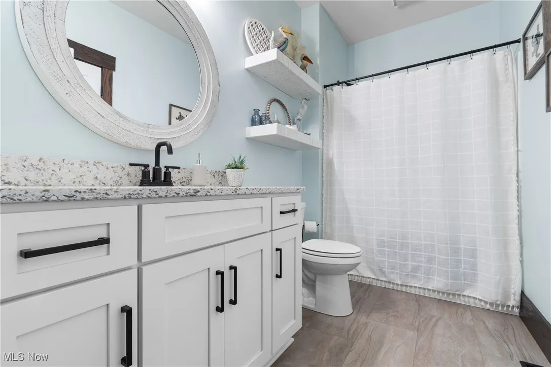 Bathroom featuring vanity and shower / bathtub combination with curtain