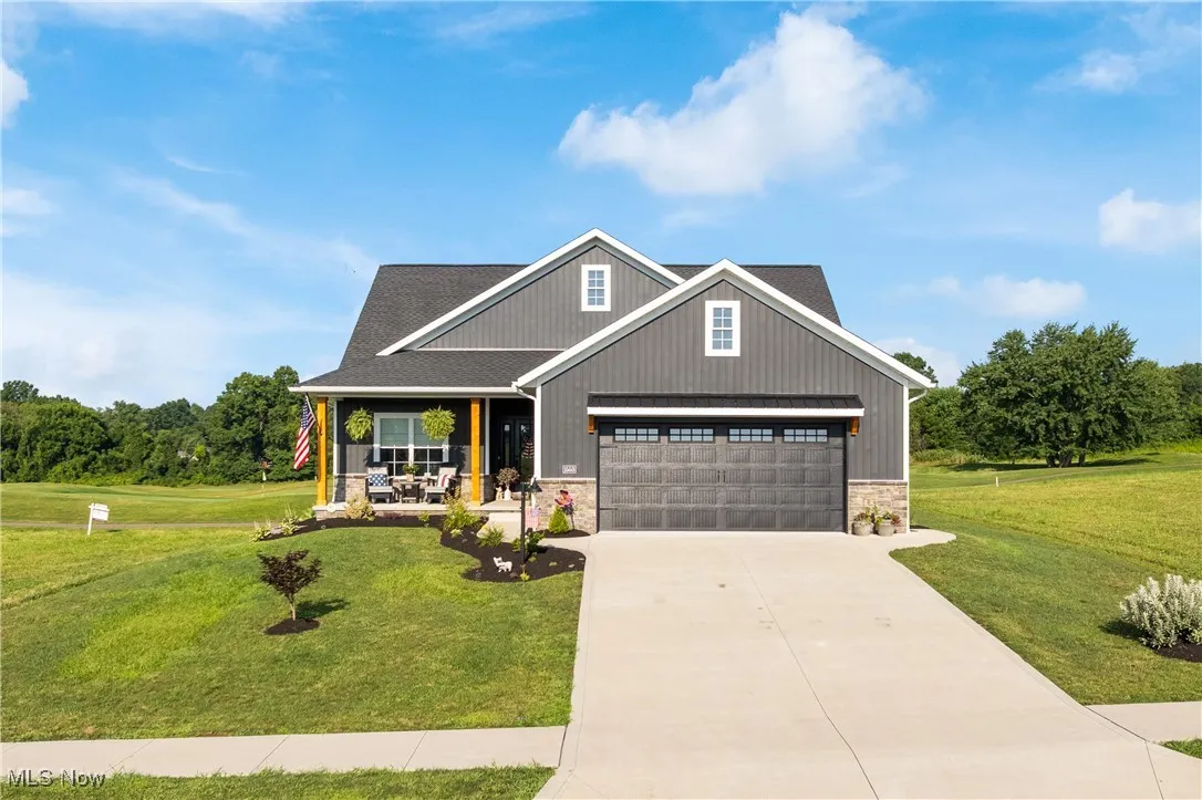 Craftsman-style house with covered porch, stone siding, a front yard, and concrete driveway