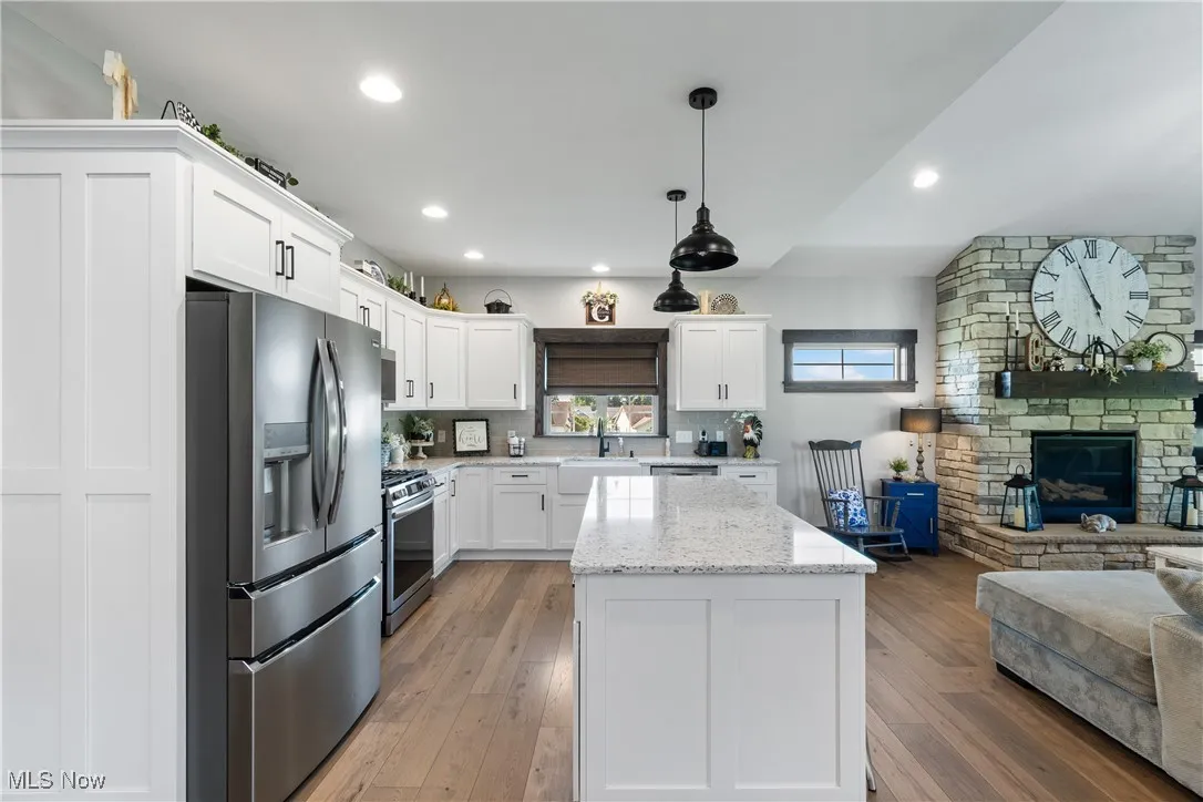 Kitchen with appliances with stainless steel finishes, open floor plan, white cabinetry, dark wood finished floors, and a center island