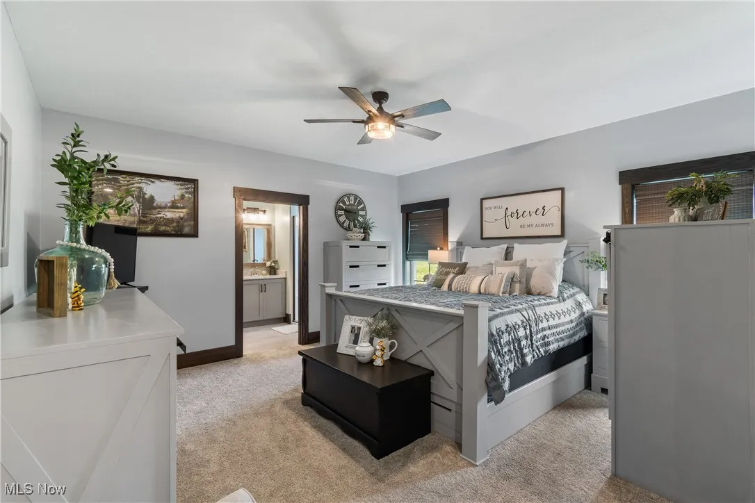 Bedroom featuring light carpet, ceiling fan, and ensuite bath