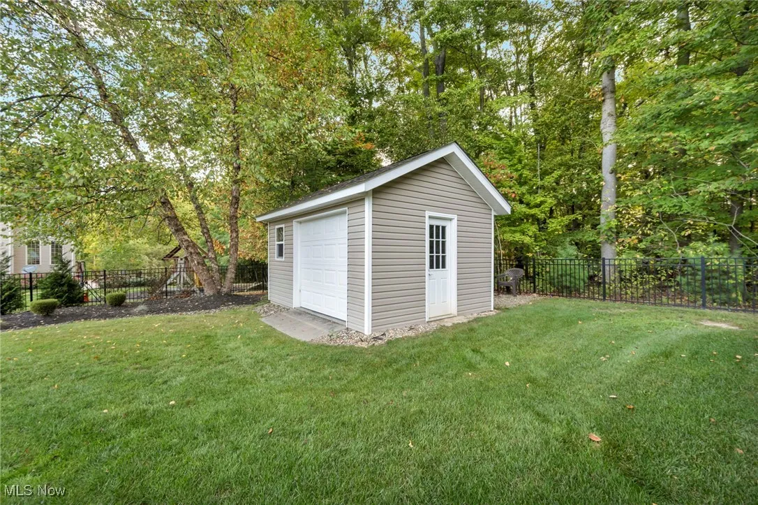 View of outbuilding with a fenced backyard and view of wooded area