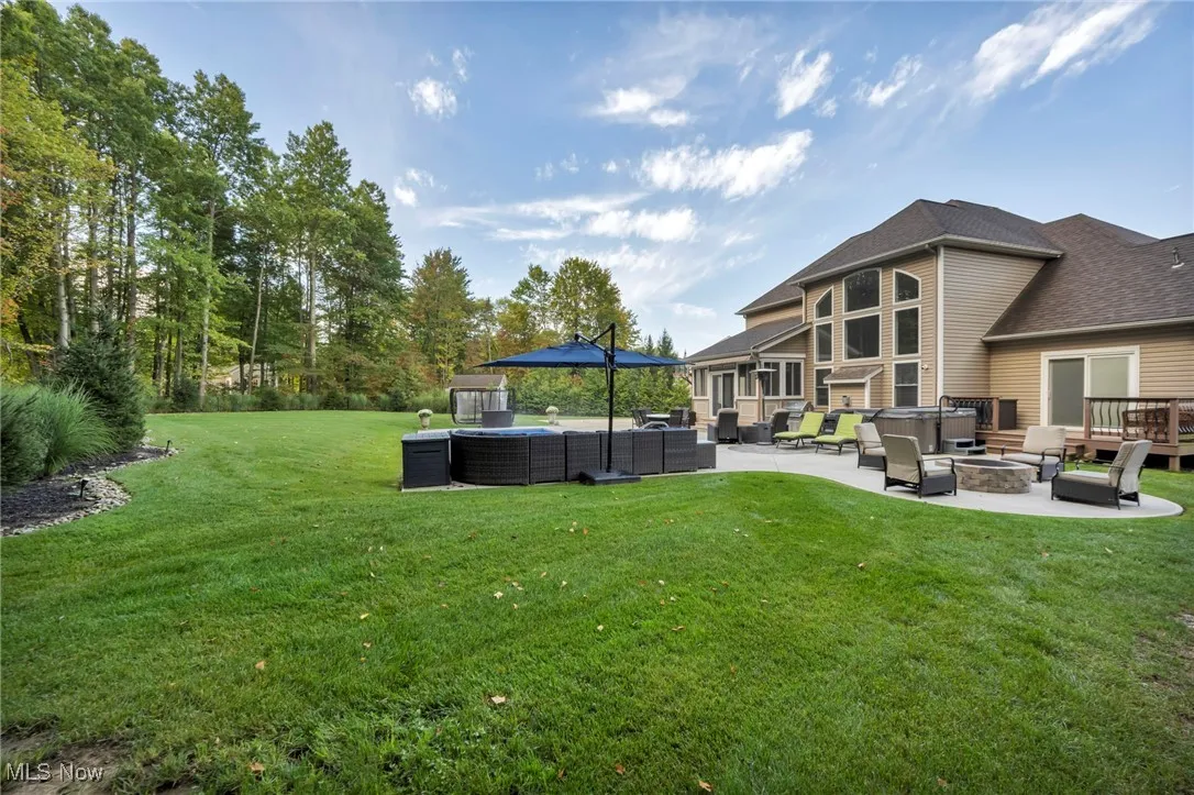 View of grassy yard with an outdoor living space with a fire pit and a patio area