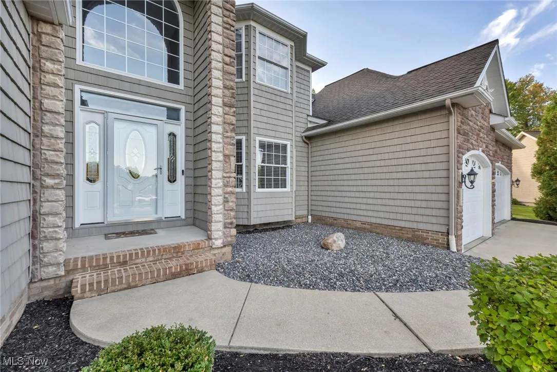 Doorway to property with an attached garage and roof with shingles