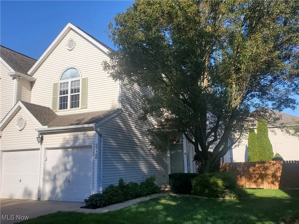 View of side of property with a garage, roof with shingles, and concrete driveway