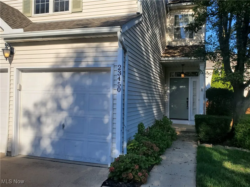 Property entrance with an attached garage and a shingled roof