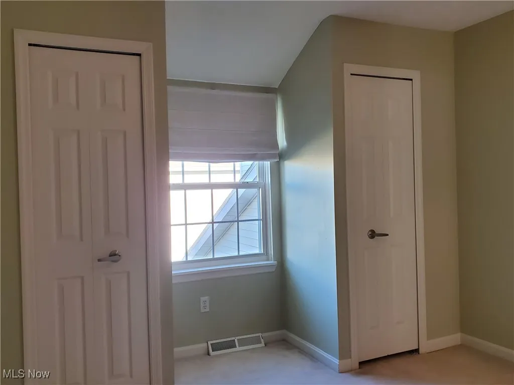 Unfurnished bedroom with baseboards and light carpet