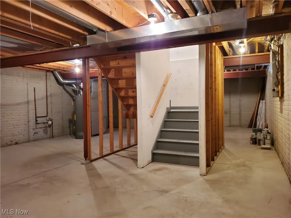 Unfinished basement with stairway and water heater
