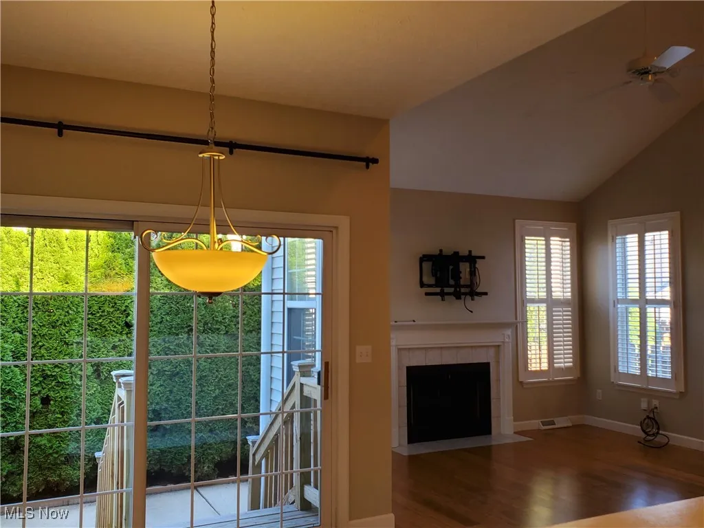 Dining room with a fireplace, wood finished floors, lofted ceiling, and ceiling fan