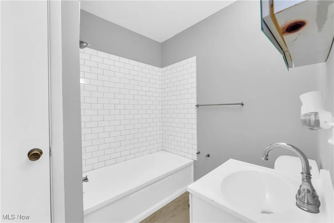 Full bathroom with shower / tub combination, vanity, and light wood finished floors