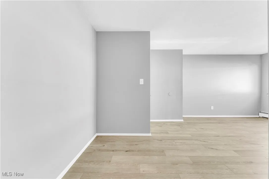 Unfurnished room featuring light wood finished floors and baseboards