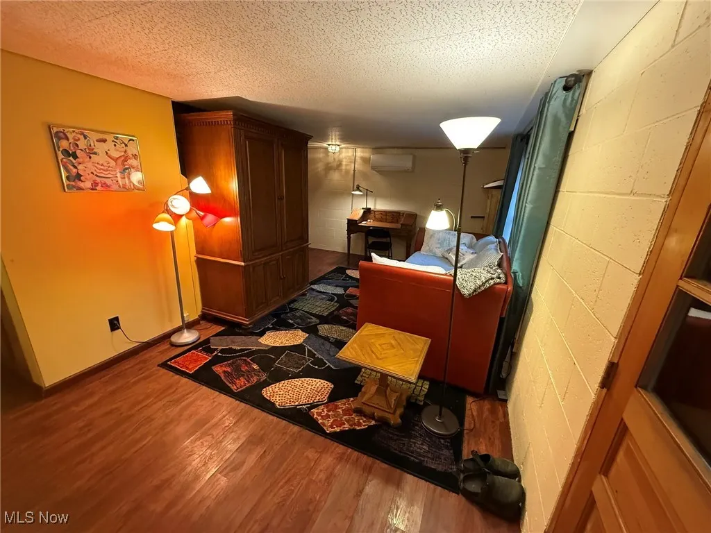 Bedroom with concrete block wall, wood finished floors, and a textured ceiling