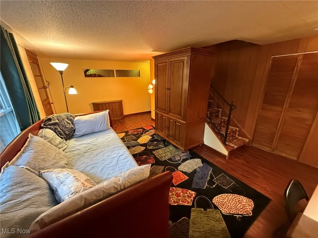 Living area with dark wood-style flooring, stairway, and a textured ceiling