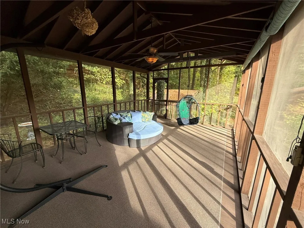 Unfurnished sunroom with lofted ceiling, ceiling fan, and a wooden deck