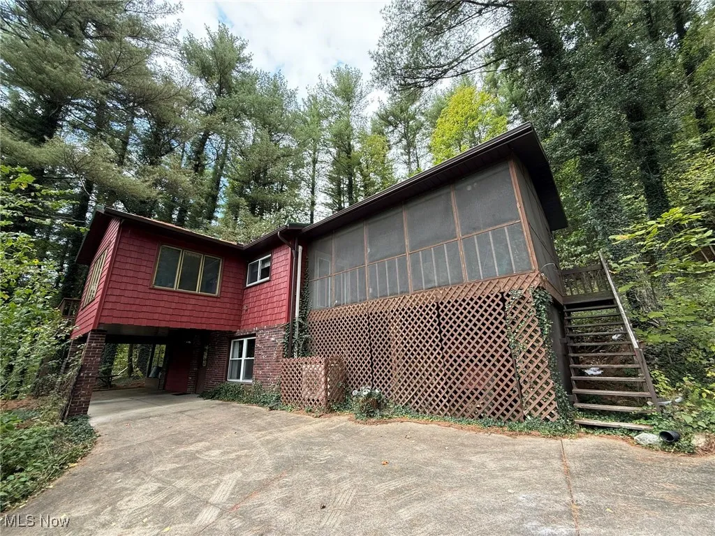 View of front of property featuring a sunroom, stairway, concrete driveway, and a carport