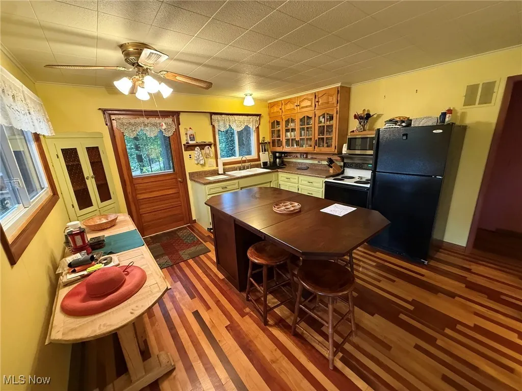 Kitchen featuring freestanding refrigerator, range with electric cooktop, a ceiling fan, glass insert cabinets, and dark wood-style flooring