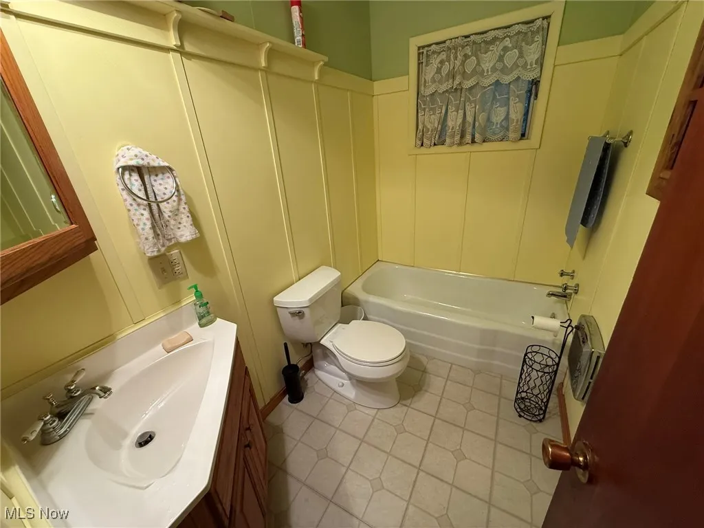 Bathroom featuring vanity, shower / tub combination, and light tile patterned flooring