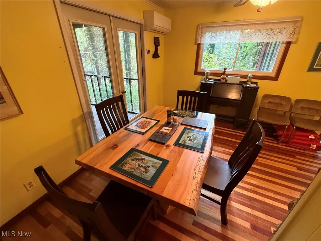 Dining area featuring dark wood-style flooring and a wall unit AC