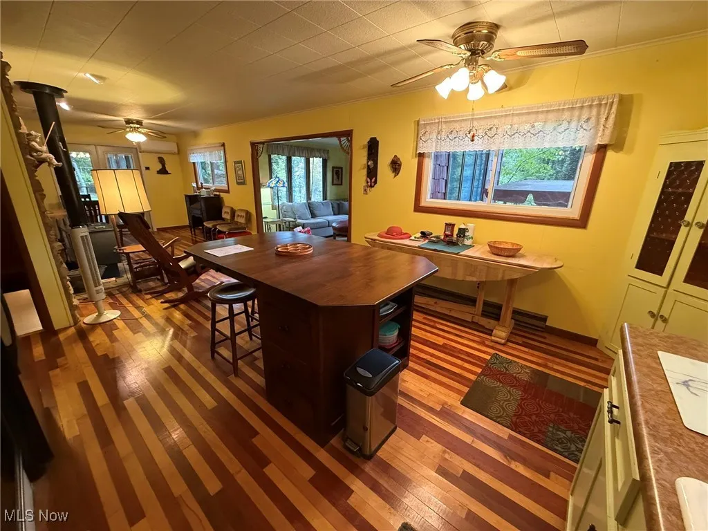 Dining space featuring ceiling fan, dark wood-style flooring, and ornamental molding