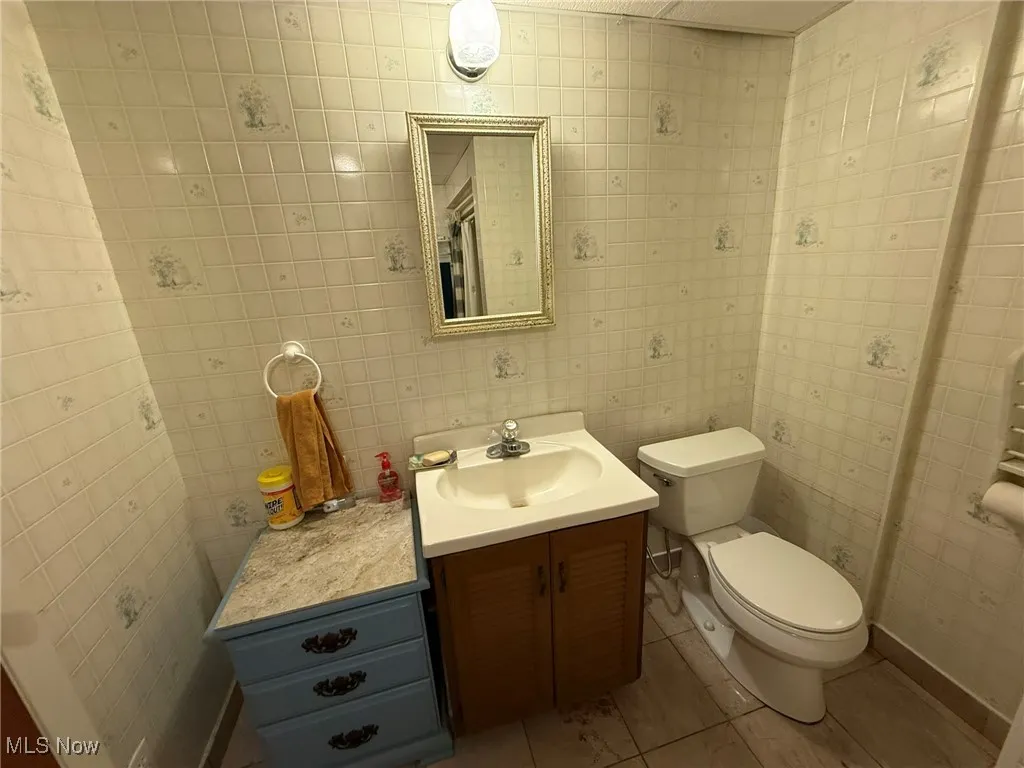 Half bath with vanity and tile patterned flooring