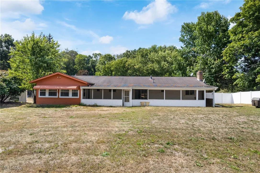 Rear view of house featuring a sunroom and a chimney