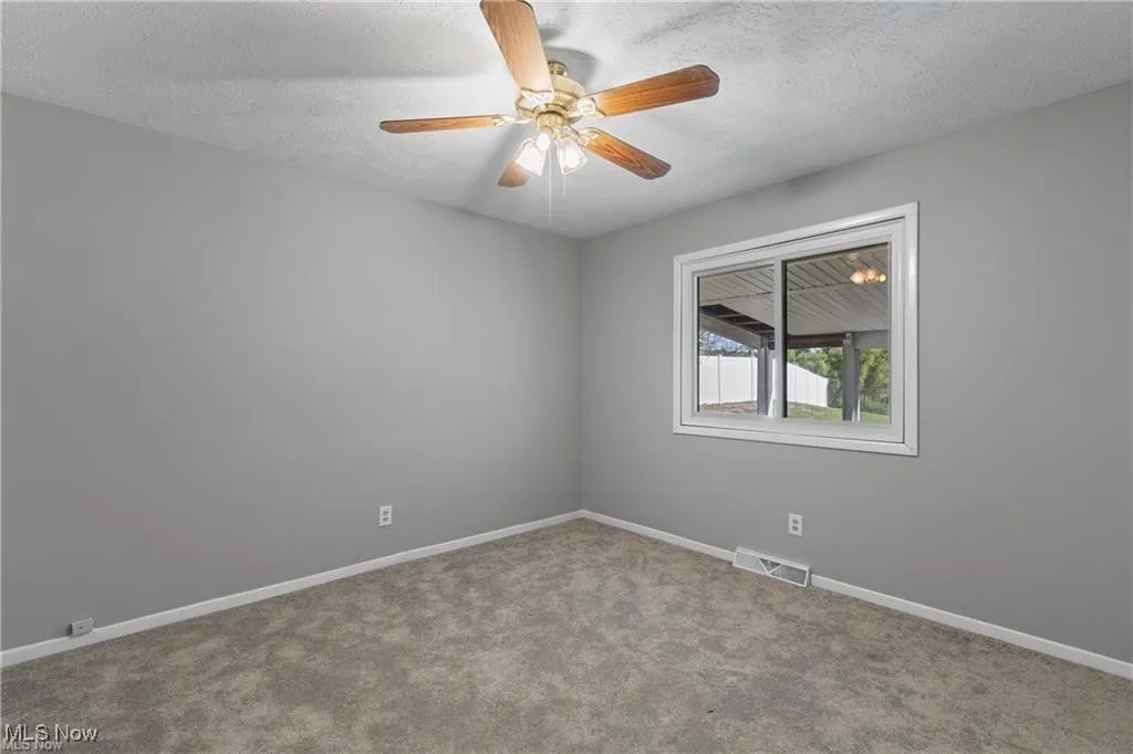 Spare room with a textured ceiling, carpet, and a ceiling fan
