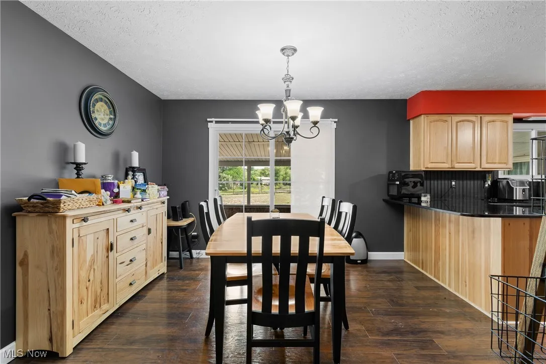 Dining room featuring a chandelier, dark wood finished floors, and a textured ceiling