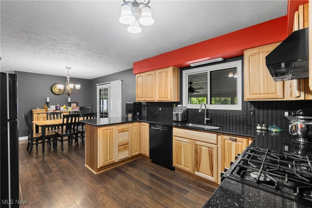 Kitchen with a chandelier, light brown cabinets, a textured ceiling, backsplash, and black appliances