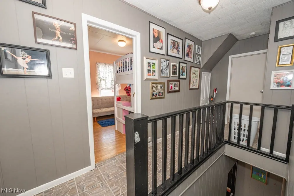 Corridor featuring wooden walls and an upstairs landing