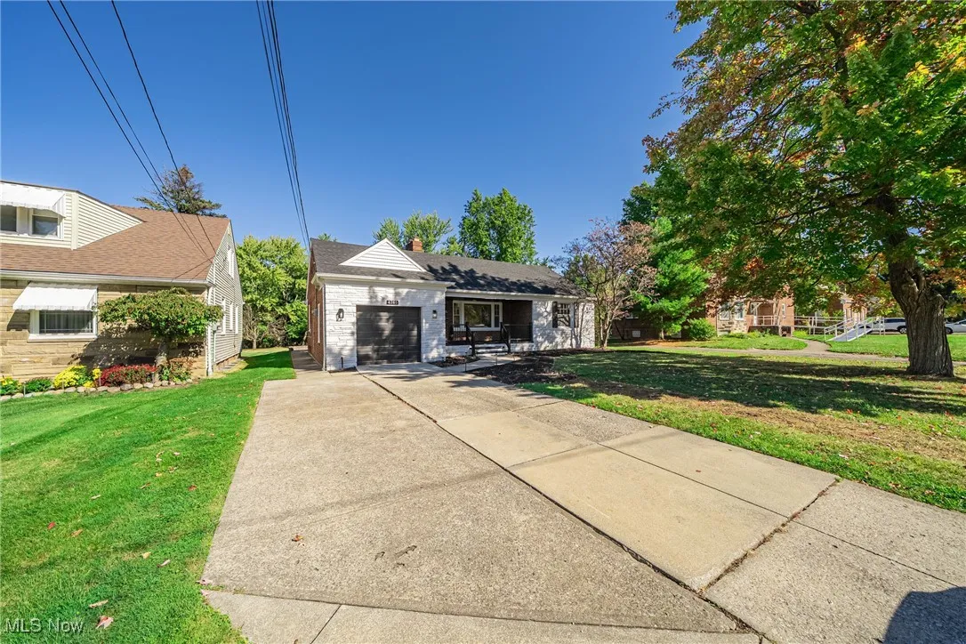 View of front facade with a front lawn, driveway, an attached garage, and a chimney
