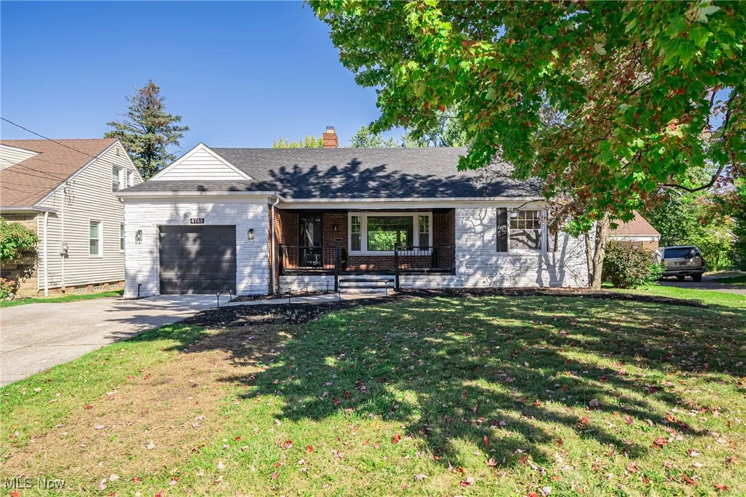 Single story home featuring covered porch, driveway, a garage, a front yard, and brick siding